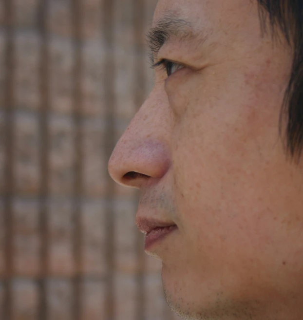 an asian man with black hair looks to his left