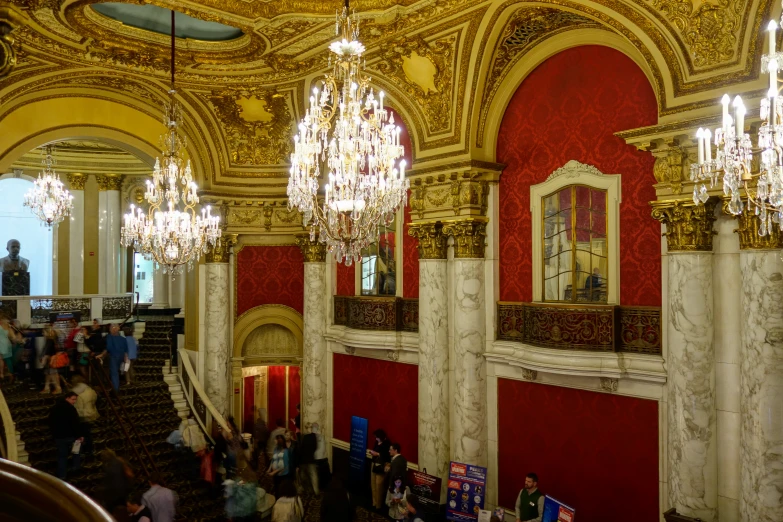 a red and gold hall with many chandeliers