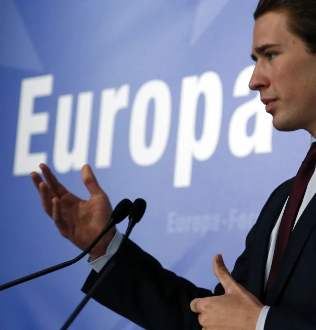 a man stands in front of a microphone in front of a european sign