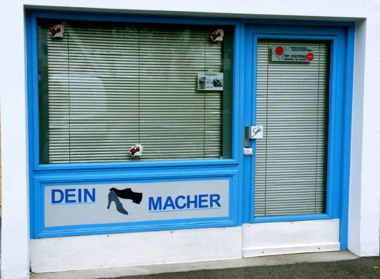 a blue window with some blind ds and the word den machher