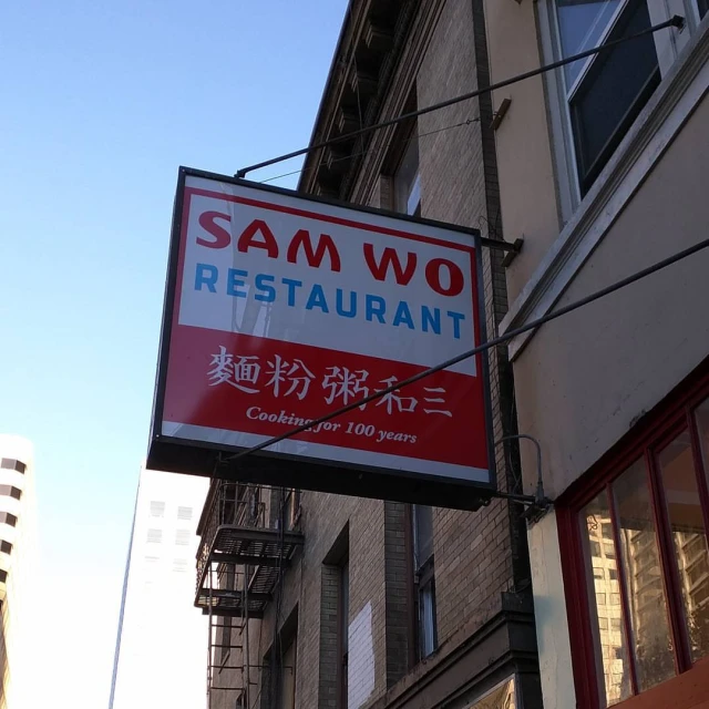 a restaurant sign for sam wo is hanging from the side of the building