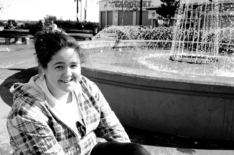 a woman sitting outside near the water fountain