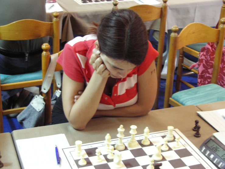 a woman is sitting at a table playing chess