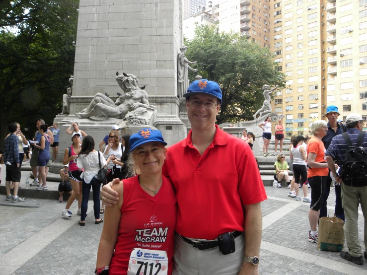 man and woman posing with city's stone statue in background