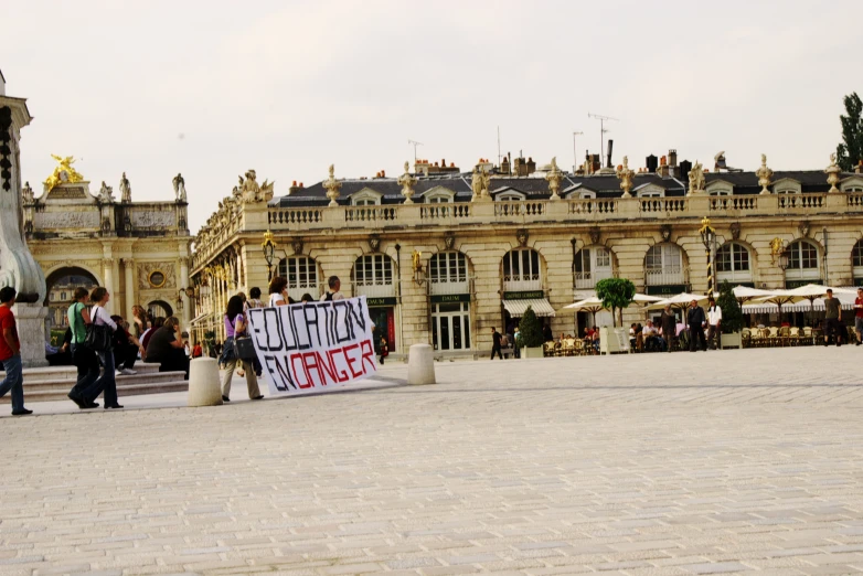 people gathered around a large building with a protest sign