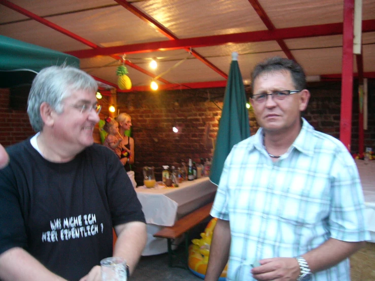 two men standing next to each other holding glasses