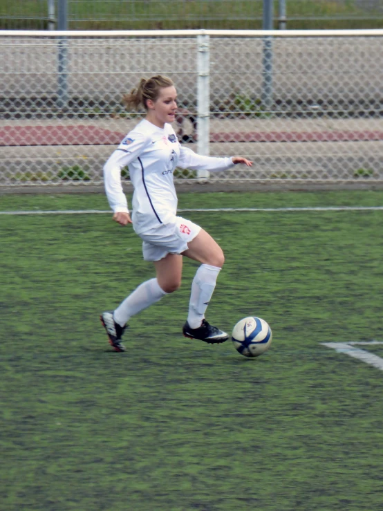 a woman on a field kicking a soccer ball