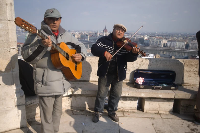 two men with musical instruments on a balcony