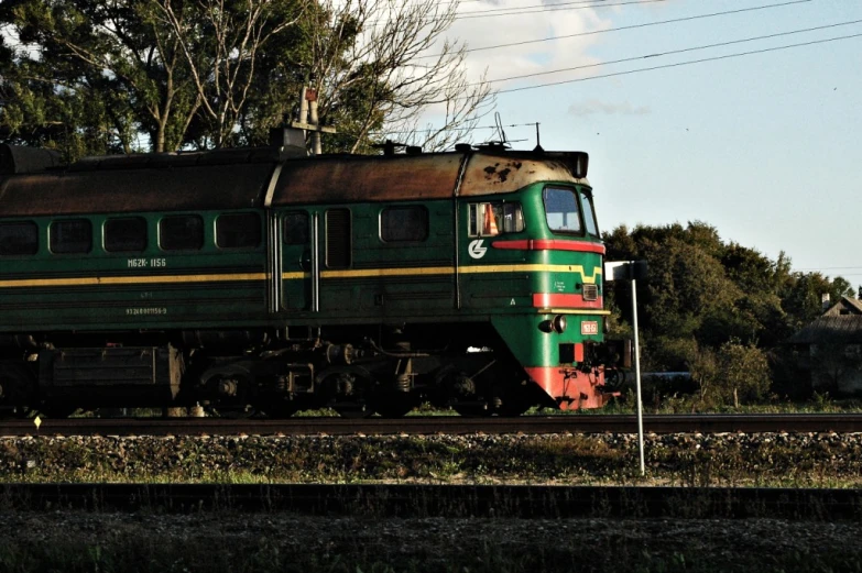 there is an old green and red train traveling down the tracks