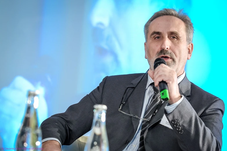 a man in a suit and tie sitting at a table with two bottles