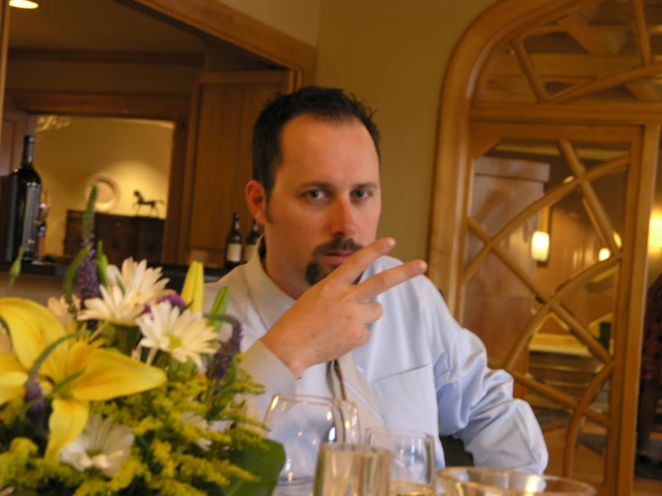 a man with a mustache sitting at a table in front of food