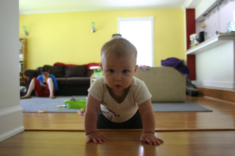 small baby crawling on the floor with one hand on his head