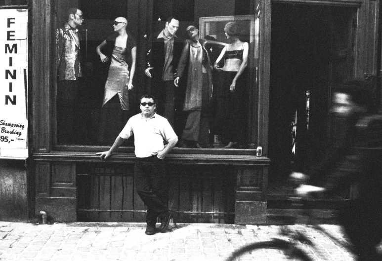 a man standing in front of a window next to bicycles