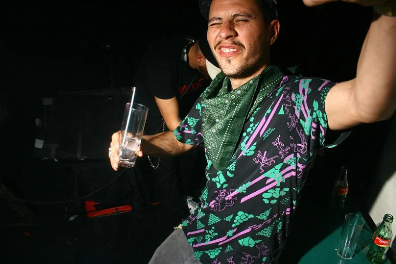 a man holding a small glass with alcohol in it