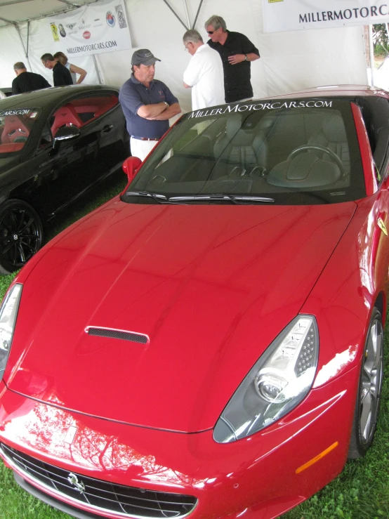 the red sports car is parked under a tent