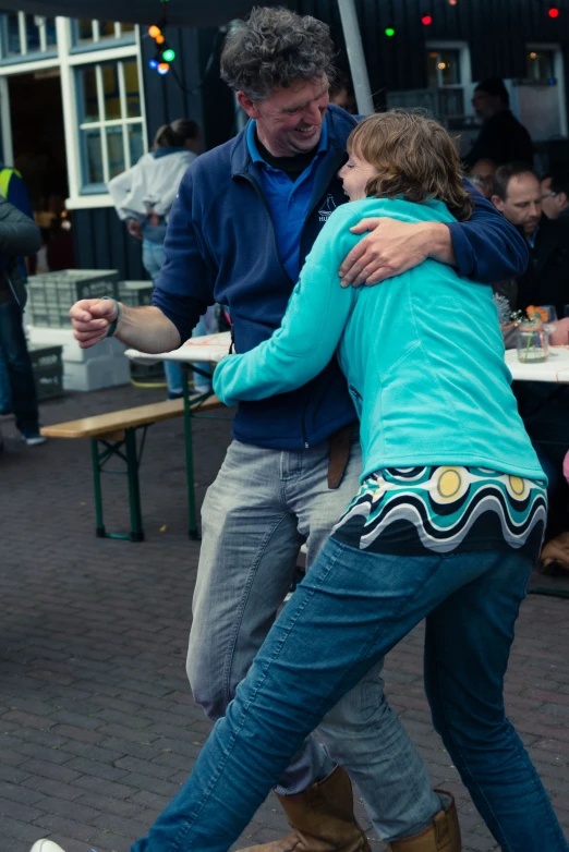 a man holding his arm around the back of a woman who is hugging her