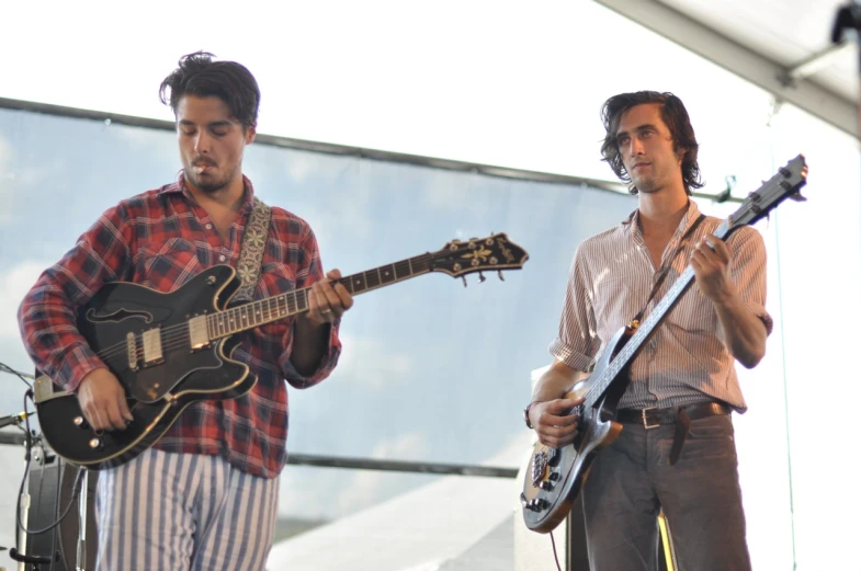 two men playing guitars while standing next to each other