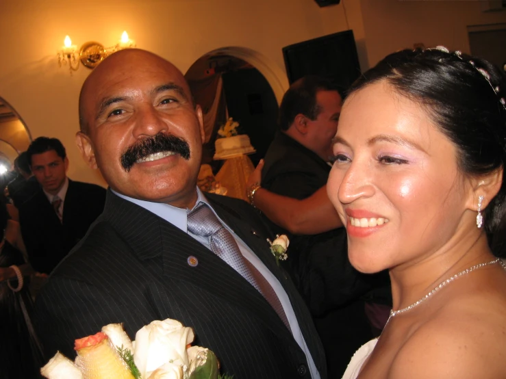 a couple smile for the camera with their wedding guests