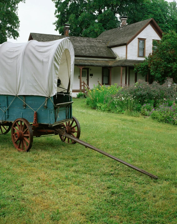 an old wagon with a covered top sits in the grass