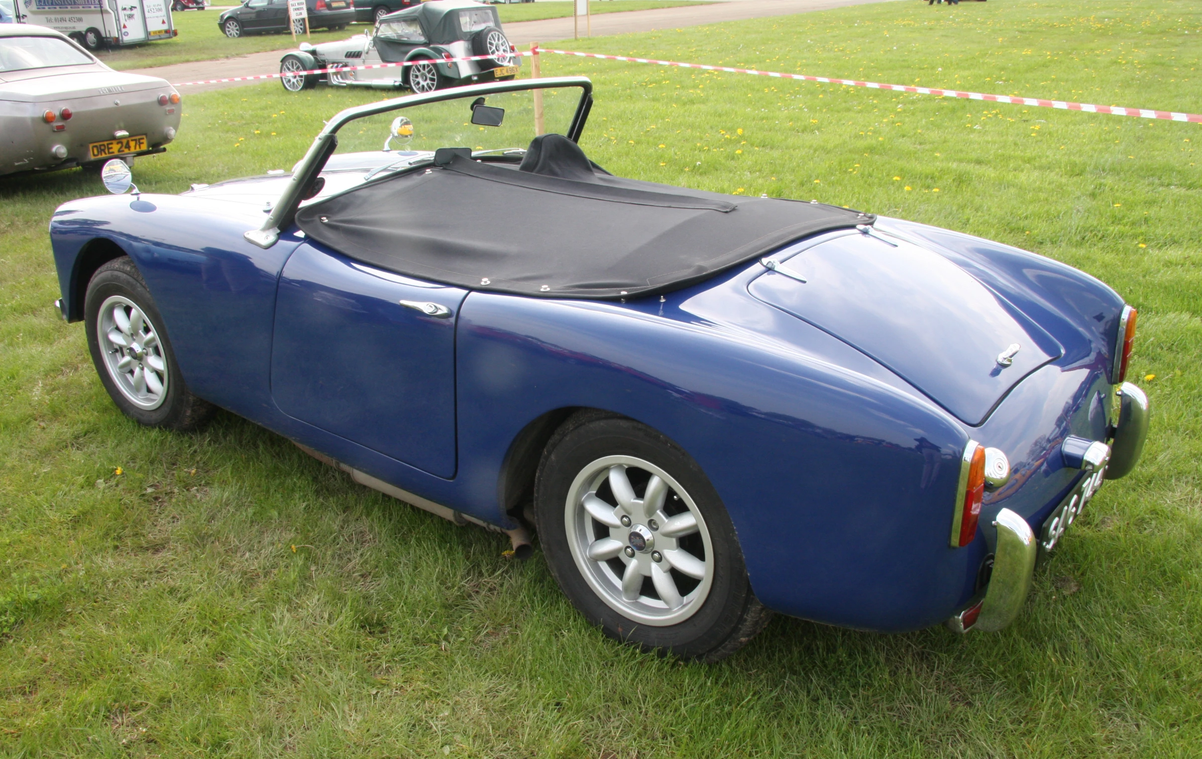 an old style sports car is parked in the grass