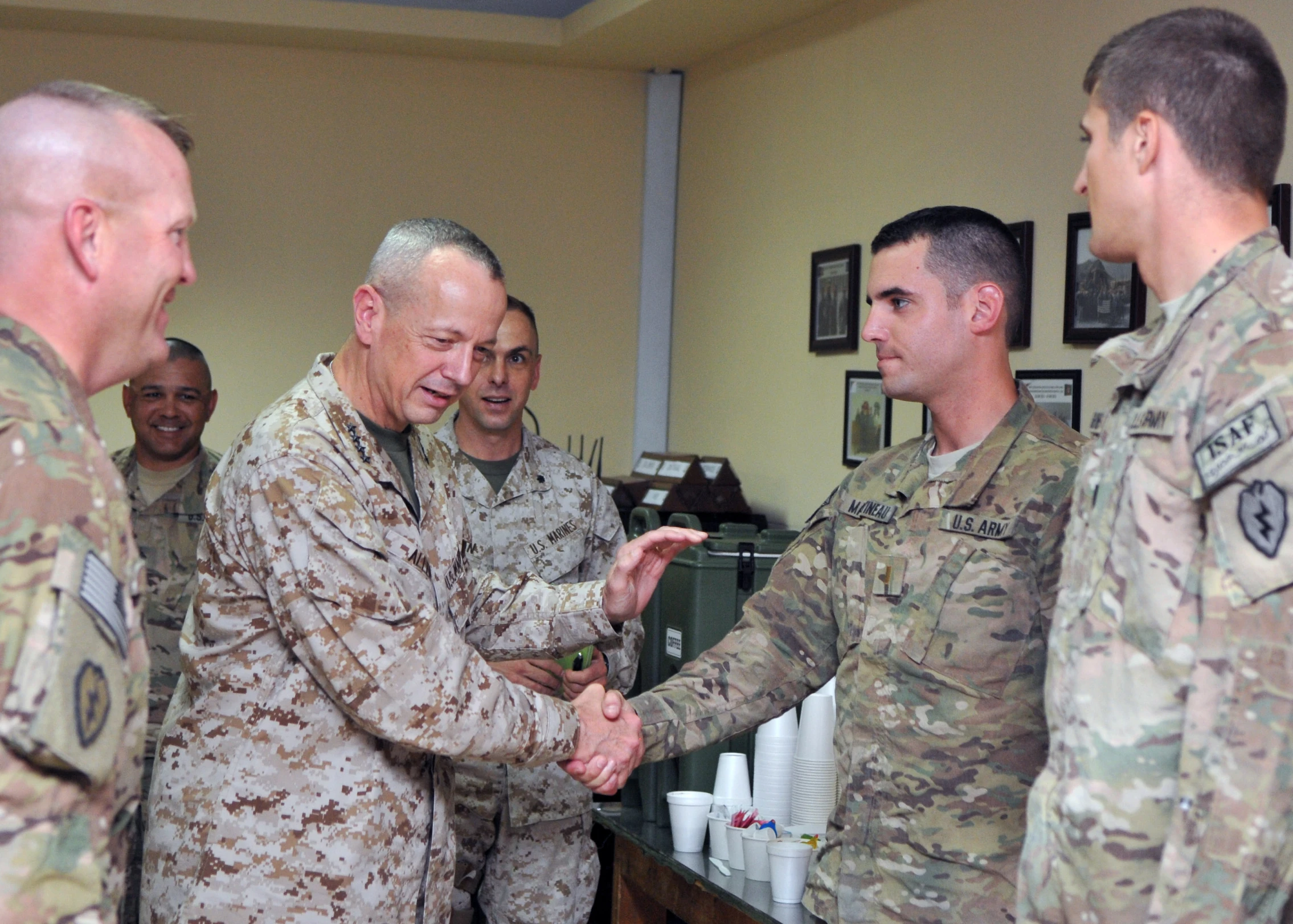 military men in suits and hats shake hands in a room