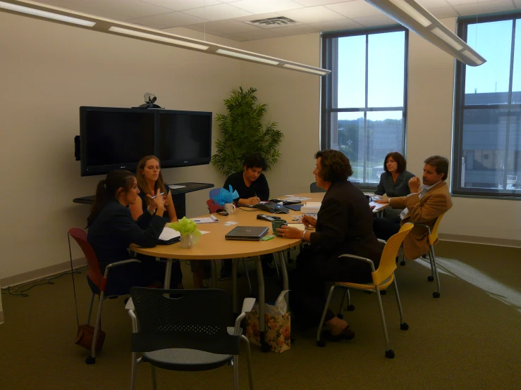 a group of people are seated around a round table