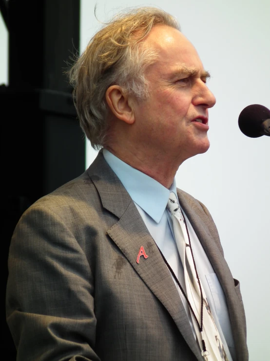 an image of a man in a suit talking into a microphone