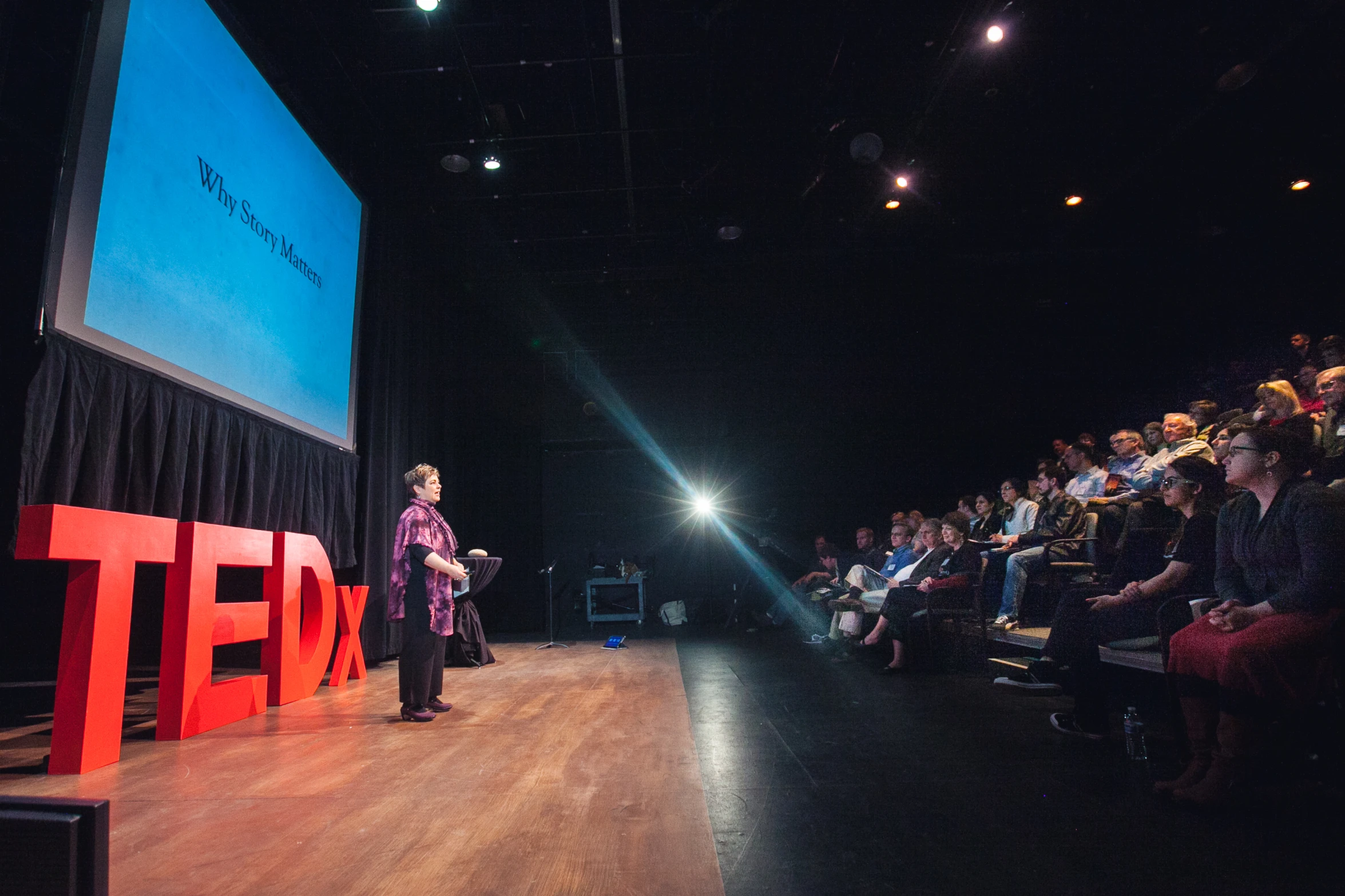 a person speaking at a conference on a stage in front of people