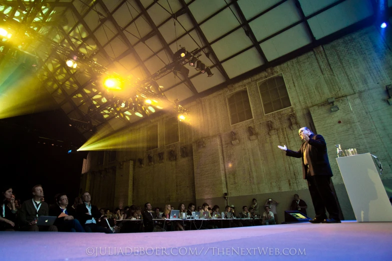 a man on stage with spotlights shining on his face