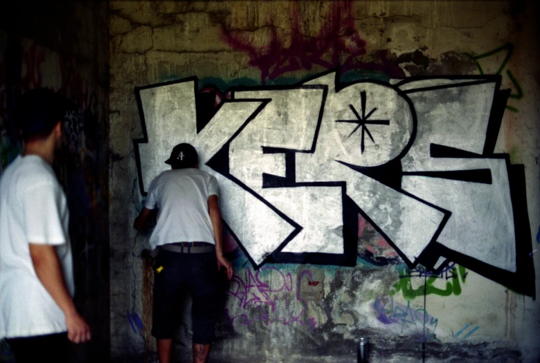 two guys are painting graffiti on a wall