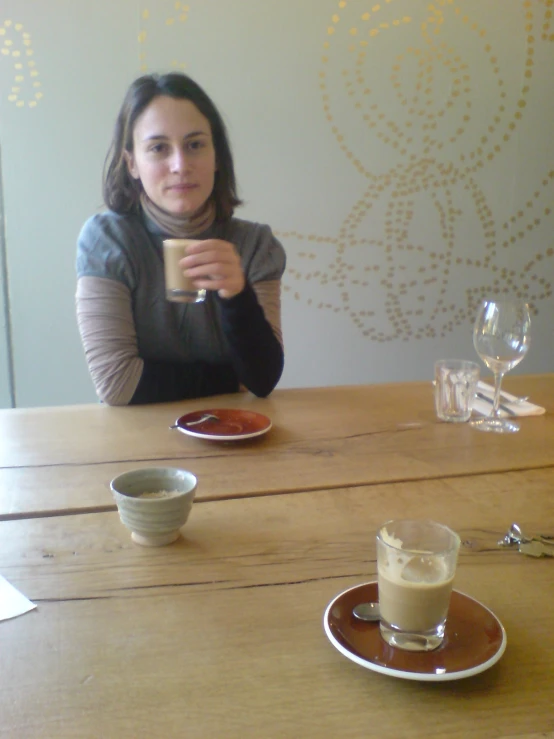 woman sitting at table with coffee cup and plate in front of her