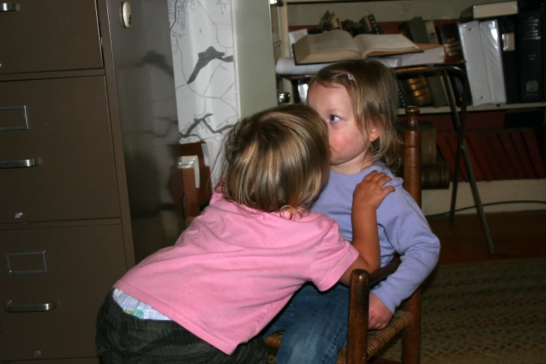 two children sitting in a chair touching the back of another child