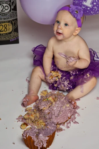 a baby girl eats a purple frosted cake