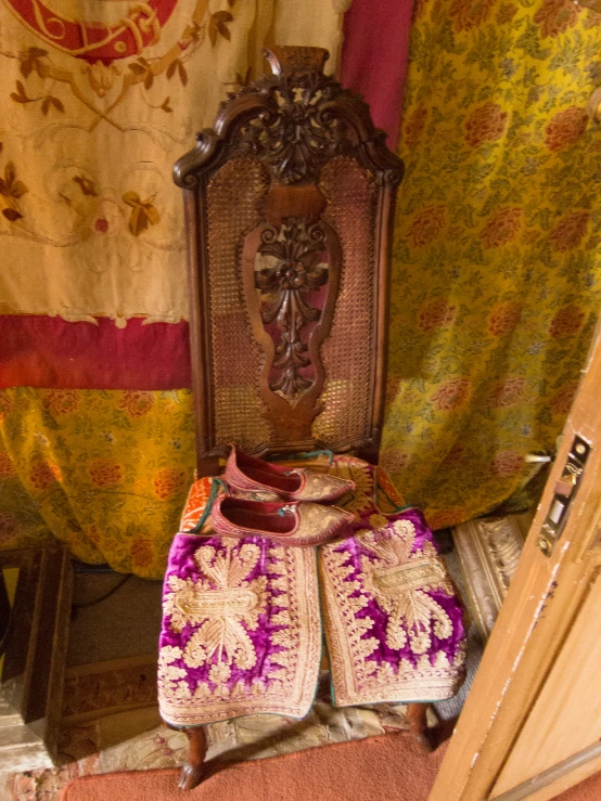 an antique chair and a mirror with foot stools next to a curtain