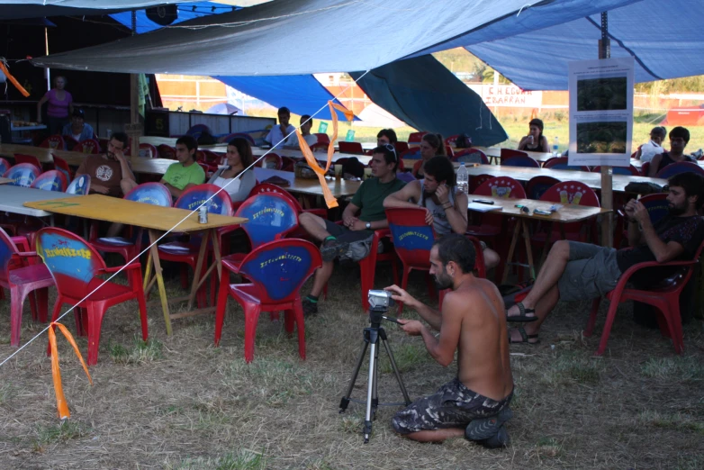 a camera man filming a group of people in a tent