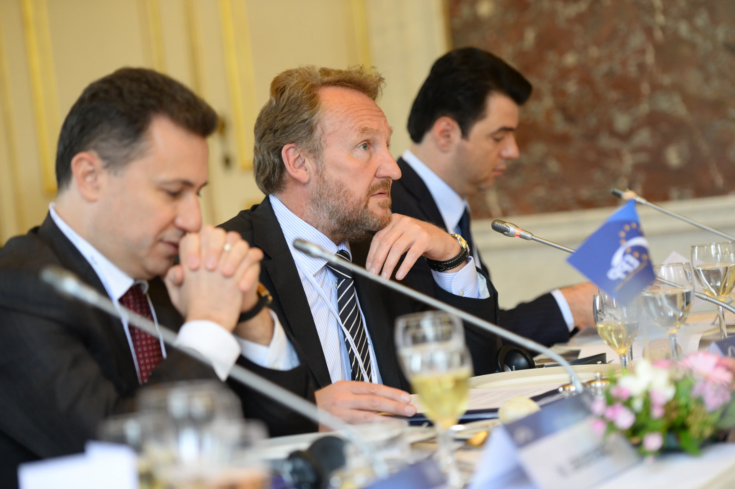 three men sitting at a table with wine glasses