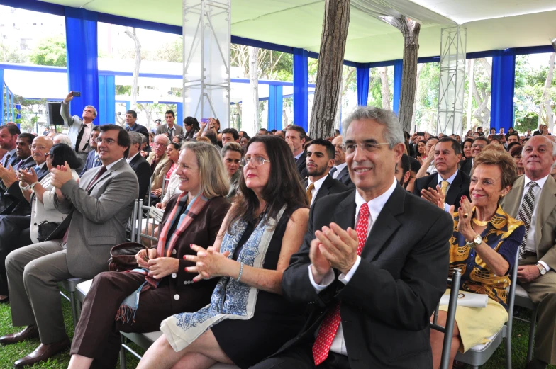 a crowd sitting in chairs applauding an audience