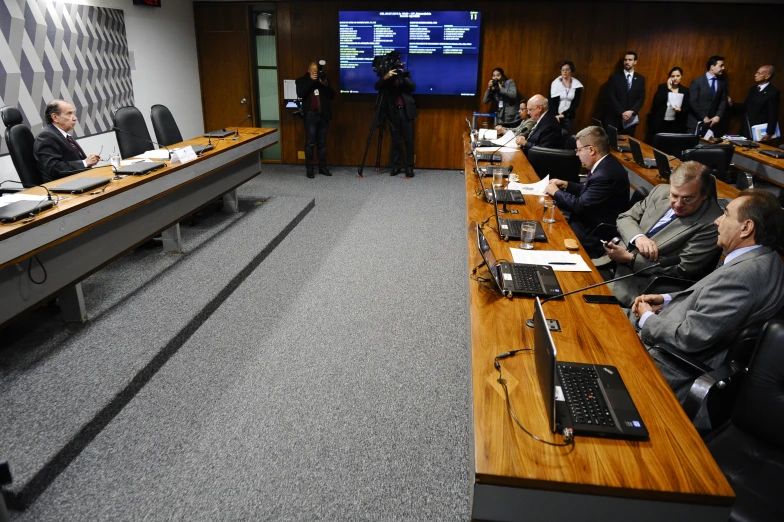 group of people sitting in the middle of a room in front of laptop computers