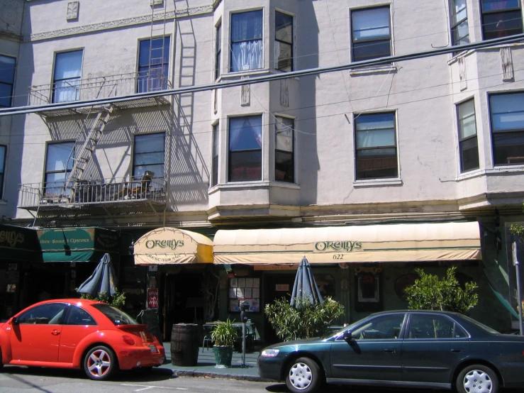 two cars are parked along the side of a street near a building