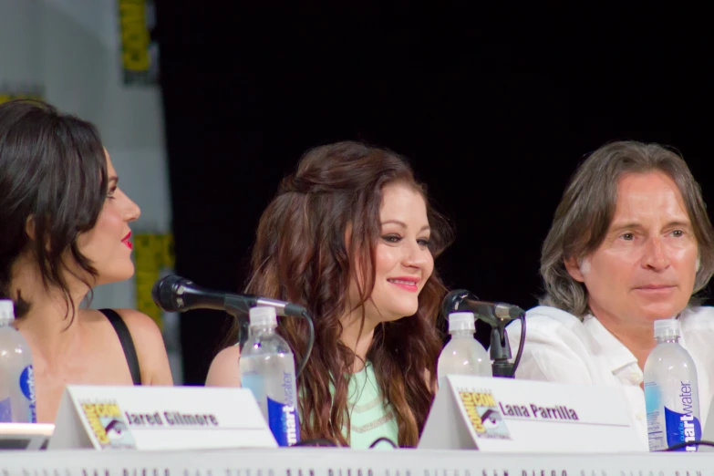 two women sit in front of microphones with water bottles