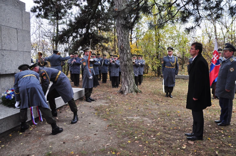 a group of people standing in a tree lined cemetery