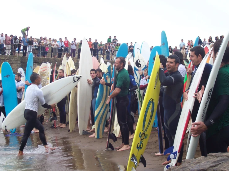 a group of people in wet suits holding surfboards on the beach