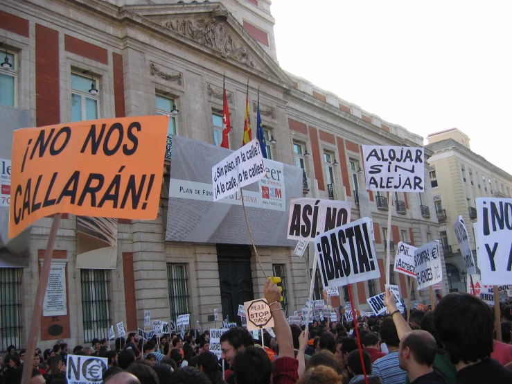 many people standing near a building holding signs