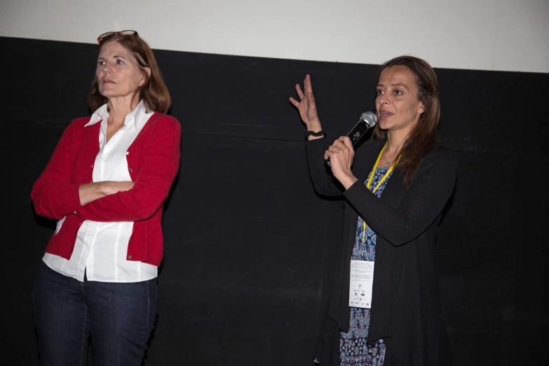 two women talking on a stage in front of microphones