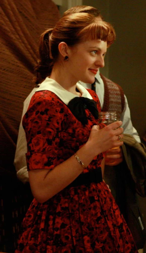 a young woman wearing a red dress and holding a wine glass
