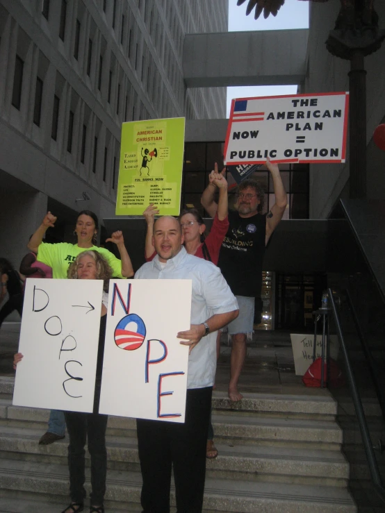 some people stand on a set of steps holding signs