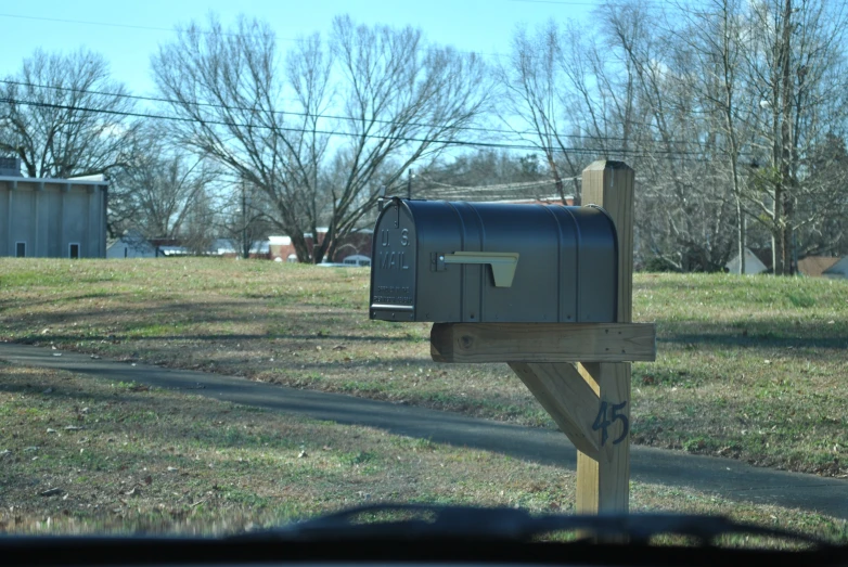 a mailbox in a yard with a fence and farm in the background