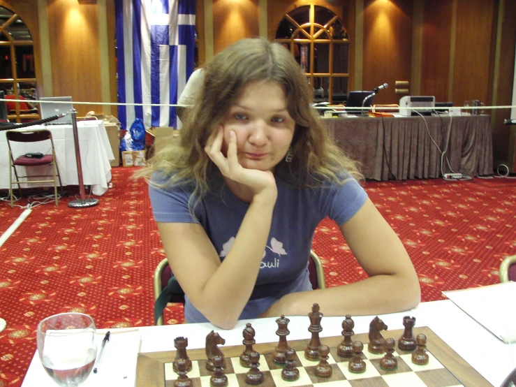 the young lady is playing chess at the table