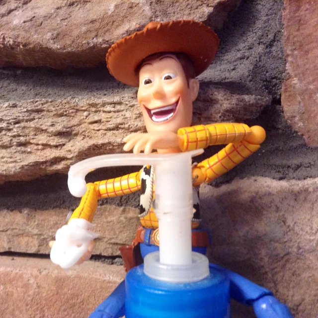 a plastic toy man standing on top of a blue watering can