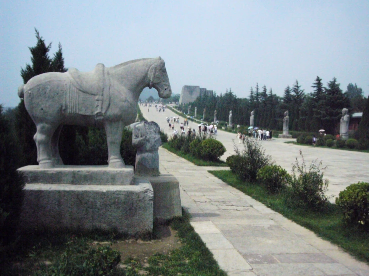 there is a horse statue in the grass on the sidewalk